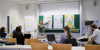 Pictured is the PRAESCO Consortium. Prof. Dr. Frauke Mörike points to posters and leads a discussion in front of a plenary audience.