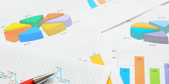 Bunte Kreis- und Balkendiagramme und ein Graph im Detail auf verschiedenen Seiten, die übereinander liegen. 